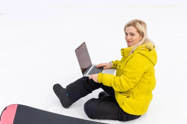 Mulher sentada com laptop em f uma montanha de inverno contra uma paisagem de fundo — Fotografia de Stock