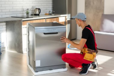 Usta bulaşık makinesini mutfak dolabına yerleştiriyor.