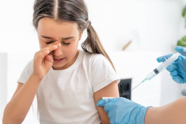 Hemşire küçük kız hastaya aşı yapıyor.