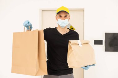 Karton kutuları tıbbi lastik eldiven ve maskeyle taşıyan teslimatçı. kopyalama alanı. Hızlı ve ücretsiz teslimat. İnternetten alışveriş ve ekspres teslimat. Karantina