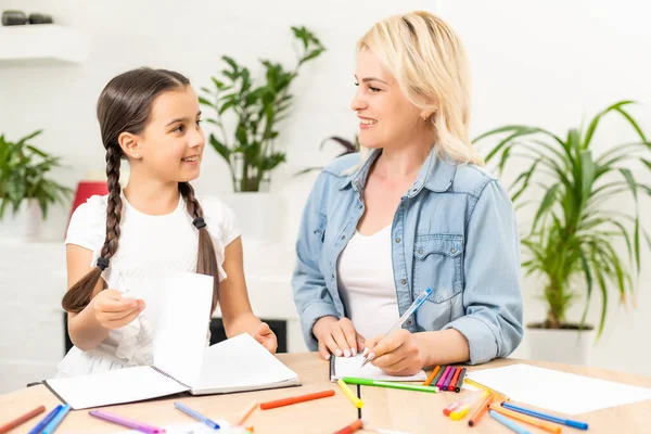 Skola flicka och mor tillsammans gör läxor i hemmet — Stockfoto