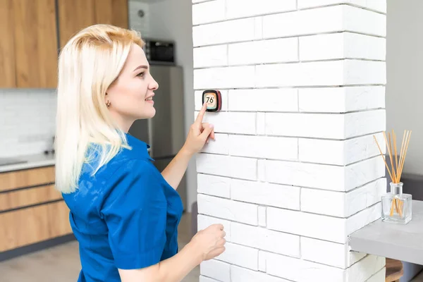 Pantalla táctil de termostato digital para el hogar inteligente mujer que toca la pantalla táctil para ajustar la temperatura de calefacción en la pared de la sala de estar — Foto de Stock