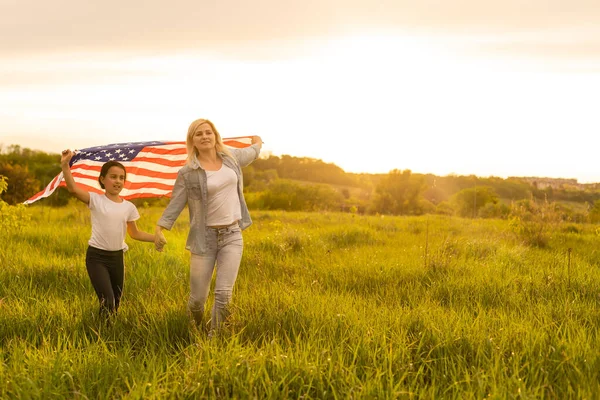 Patriotic holiday. Happy family, mother and her daughter child girl with American flag outdoors. USA celebrate 4th of July — Stock Photo, Image