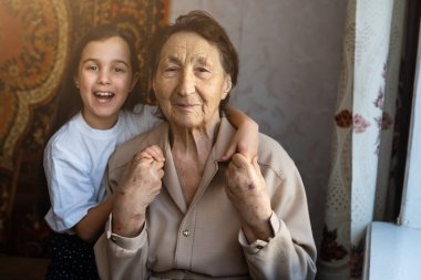 Küçük bir kız bebek ve çok yaşlı bir kadın. Küçük çocuk büyükannesine sarılıyor. Torunum.