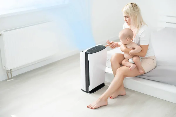 Mother and baby near air purifier at home. — Stock Photo, Image