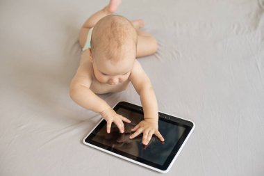 Bebek beyazı izole edilmiş dijital tabletle oynuyor