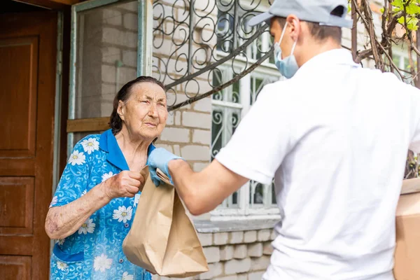 Oudere vrouw betaalt koerier van voedselleverancier voor bestelling via terminal. Begrip epidemie — Stockfoto