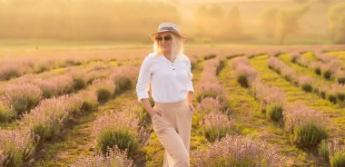 Lavanta tarlasında saman şapkalı genç sarışın gezgin lavanta çiçekleriyle çevrili..