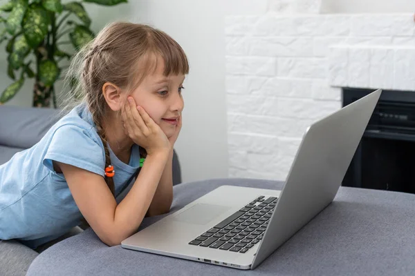 Dálkové studium. Veselá holčička ve sluchátkách pomocí notebooku studuje prostřednictvím online e-learningového systému. — Stock fotografie