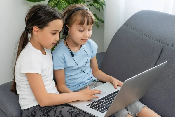Dvě dívky pracující na notebooku, usmívající se a starší sestra pomáhat mladší — Stock fotografie