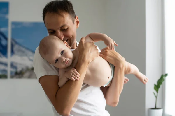 Fader kramar det nyfödda barnet i vitt sovrum. — Stockfoto