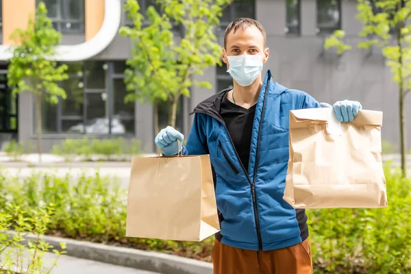 Hispánec mladý donáška muž nosí masku obličeje při nošení balíček box během epidemie coronavirus. — Stock fotografie