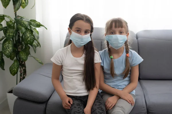 Indoor shot of little girls with wide opened eyes, wearing protective mask, Protection against coronavirus, covid 19 concept — Stock Photo, Image