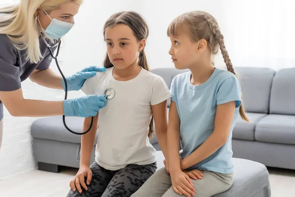 Junge Ärztin mit kleiner Patientin fühlt sich schlecht ärztliche Untersuchung mit Stethoskop. — Stockfoto