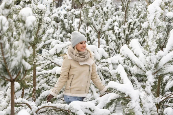 Νεαρή γελαστή καυκάσια γυναίκα και πεύκα στο χειμερινό δάσος. Θετικά συναισθήματα, περπάτημα σε χιονισμένο καιρό — Φωτογραφία Αρχείου
