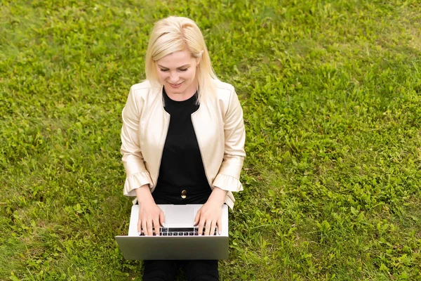 Женщина с ноутбуком отдыхает в парке — стоковое фото