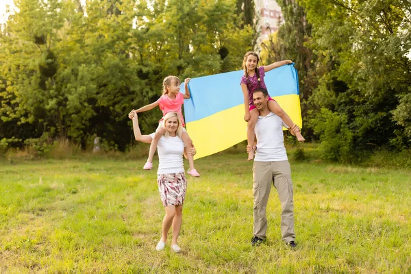 Família feliz com bandeira de ucraniano no campo. estilo de vida — Fotografia de Stock