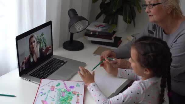 Liten flicka studerar med sin mormor hemma, använda laptop för utbildning, online-studier, hem studera. Flickan har läxor på distans. Livsstilskoncept för familjekarantän covid-19. — Stockvideo