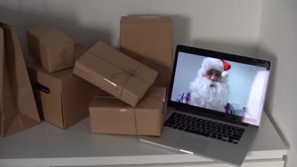 Santa Claus wideokonferencje dziecko rozmawiające z dzieckiem machając ręką pozdrowienia na Wesołych Świąt, Szczęśliwego Nowego Roku w wirtualnym wideo czat spotkanie na laptopie siedzi przy stole warsztatowym wysyłanie prezentów w Wigilię — Wideo stockowe