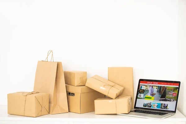 Compras en línea - Cartones de papel o paquete en un teclado portátil. Servicio de compras en la web en línea y ofrece entrega a domicilio. — Foto de Stock