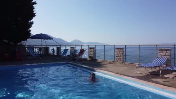 La madre con su hijita se divierte en la piscina. Mamá juega con el niño. La familia disfruta de vacaciones de verano en una piscina. — Vídeos de Stock