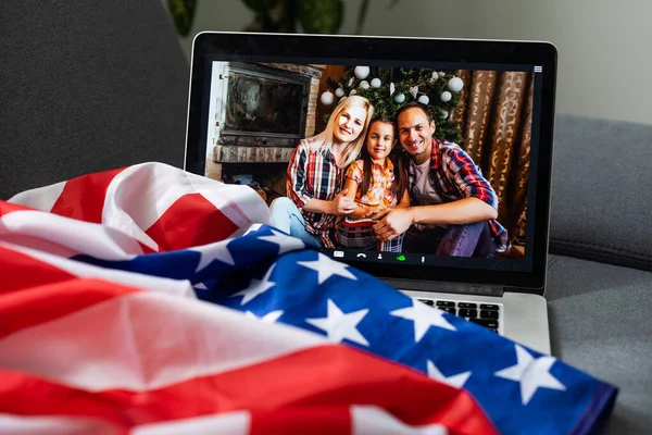 Fiesta en línea con seres queridos de Estados Unidos. Celebrando el video chat de Navidad. Fiesta virtual a través de mensajero de vídeo. Los estadounidenses de año nuevo son el chat de vídeo. Regalos de Año Nuevo y bandera de América al lado de la computadora — Foto de Stock