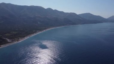 Güney Arnavutluk 'un güzel kıyı şeridi mavi gök mavisi denizin üzerindeki tepeler ve dağlarla