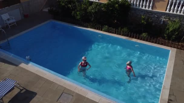 Woman and little girl in the pool. Happy family have a rest. Summer sunny day. — Stock Video