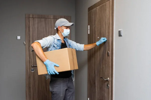 Αρχική παράδοση κατάστημα κουτί άνθρωπος φορώντας γάντια και προστατευτική μάσκα παράδοση πακέτα στην πόρτα — Φωτογραφία Αρχείου