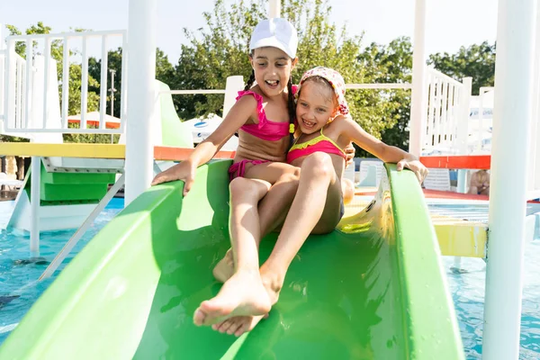 Dos chicas chapotean en una piscina al aire libre en verano. Niños felices, hermana jugando, disfrutando del tiempo soleado en la piscina pública — Foto de Stock