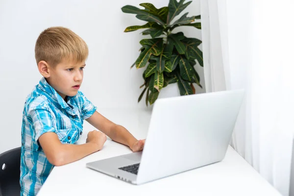 Online onderwijs op afstand. Een schooljongen studeert thuis en doet huiswerk op school. Een afstandsonderwijs thuis — Stockfoto
