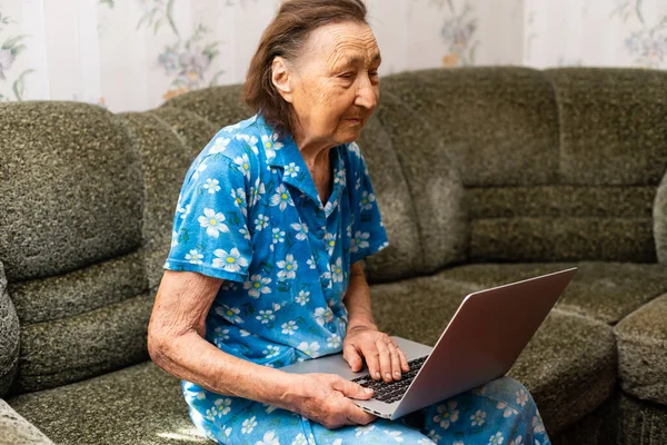 Donna molto anziana con un portatile in mano — Foto Stock