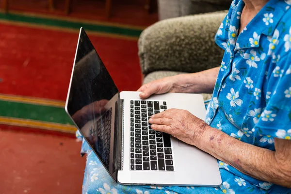 Very old woman using laptop sitting in her sofa — Stock Photo, Image