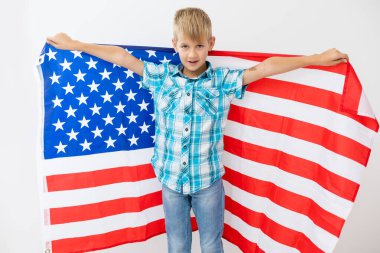 Sarışın çocuk beyaz arka planda ulusal Amerikan bayrağı sallıyor. Amerikan bayrağı, vatanseverlik, bağımsızlık günü 4 Temmuz konsepti