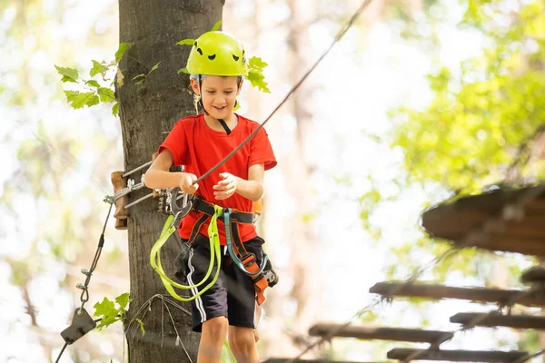 Parco avventura arrampicata alta fune - bambino in corso in casco di montagna e attrezzature di sicurezza — Foto Stock
