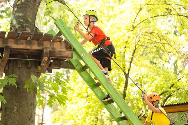 Aventura escalada alto fio parque - menino no curso em capacete de montanha e equipamentos de segurança — Fotografia de Stock