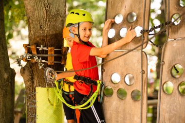 Güzel bir okul çocuğu macera parkında güneşli bir günün tadını çıkarıyor.