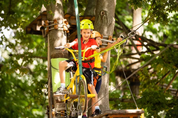 Criança feliz a subir nas árvores. Um parque de cordas. Criança alpinista. Desenvolvimento da primeira infância. Roping Park. Feixe de equilíbrio e pontes de corda. Parque de cordas - centro de escalada — Fotografia de Stock