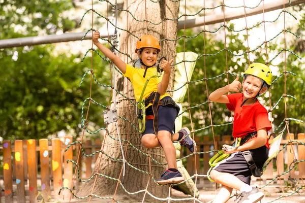 Lindos niños. Niño y niña escalando en una estructura de patio de cuerda en el parque de aventuras —  Fotos de Stock