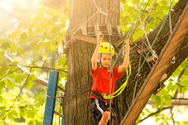 Çocuk tırmanışçı ip köprüde yürüyor,