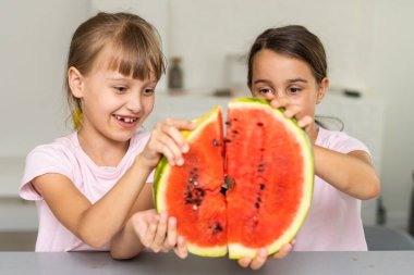 Evde karpuz yiyen iki kız.