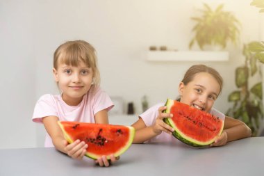 İki çocuk bir dilim karpuz yiyor. Çocuklar dışarıda meyve yer. Çocuklar için sağlıklı atıştırmalık.
