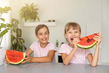 Evde karpuz yiyen iki kız.