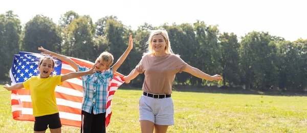 Hermosa familia con la bandera americana en un campo. Día de la Independencia, 4 de julio. — Foto de Stock