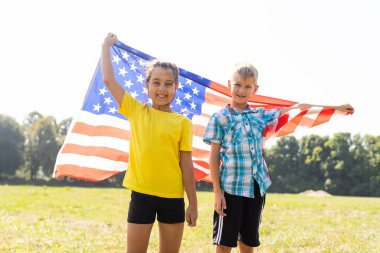 Mutlu çocuklar 4 Temmuz kutlamalarında kendilerini Amerikan bayrağıyla kapattılar. Anma Günü, Bağımsızlık Günü, Vatanseverlik Günü. ABD.