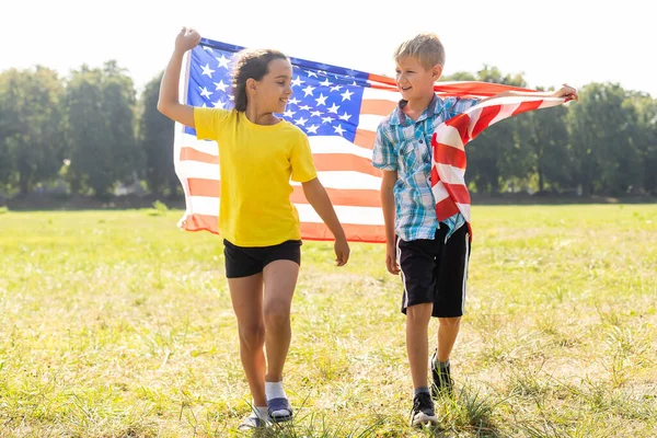 Счастливые дети, укрывшись американским флагом, празднуют 4 июля. Мемориал, День Независимости, Патриотический праздник. США. — стоковое фото