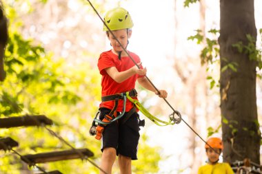 Güzel bir okul çocuğu macera parkında güneşli bir günün tadını çıkarıyor.