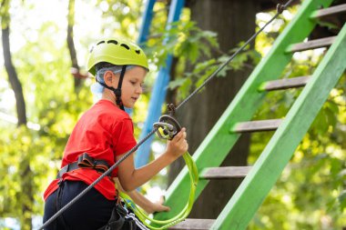 Güzel bir okul çocuğu macera parkında güneşli bir günün tadını çıkarıyor.