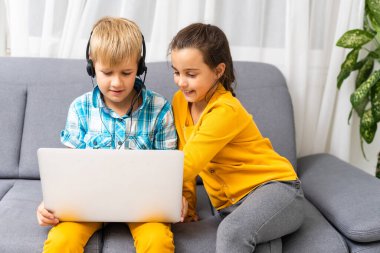 Teknoloji, arkadaşlık ve iletişim kavramını bozar. Evdeki oturma odasında kanepede otururken tablet ve dizüstü bilgisayar kullanan iki tatlı genç.
