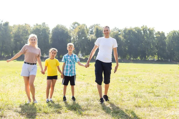 Boldog család sétál a mezőn és fogja egymás kezét — Stock Fotó